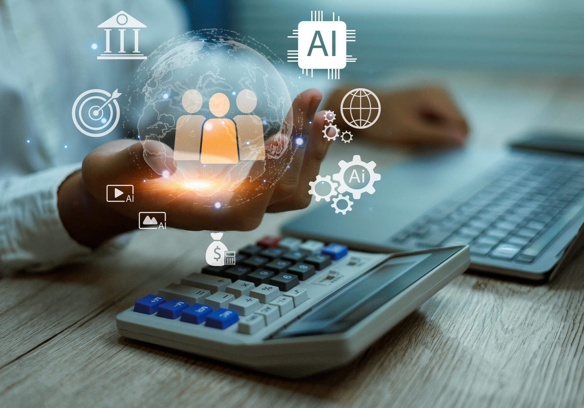 Hand holding digital icons over a calculator and laptop keyboard.